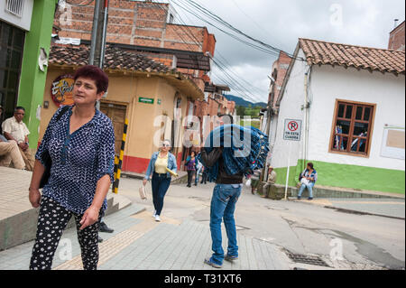 Donmatias, Antioquia, Colombia: Young transporting a towering blue pile of jeans on his shoulder. Stock Photo