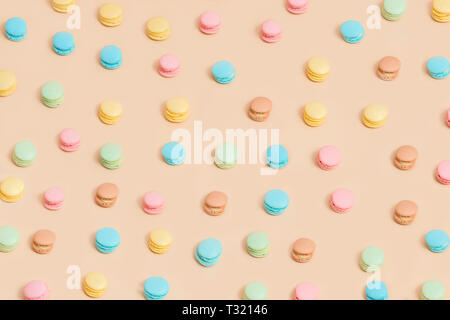 Colorful cake macaron or macaroon on cream pastel background from above. French almond cookies on dessert top view. Stock Photo