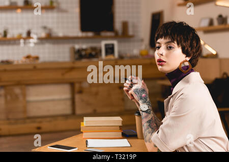 confident businesswoman sitting at table in cafe and looking away Stock Photo