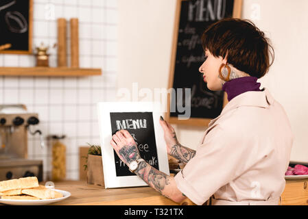 pretty businesswoman writing on menu board while standing at bar counter Stock Photo