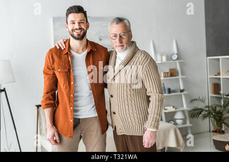 handsome man smiling while standing with cheerful senior father Stock Photo