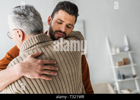 handsome bearded man hugging elder father at home Stock Photo