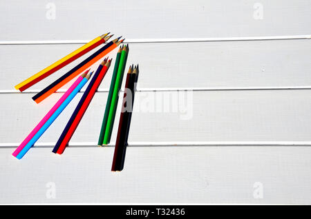 Colored pencils aligned on white pallet table Stock Photo