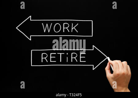 Hand writing Work and Retire on two arrows with chalk on blackboard. Concept about the decision making of an aging worker between continue working or  Stock Photo