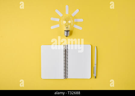 Financial planning table top with pen, notepad, light bulb on yellow background. Concept brainstorming and new idea Stock Photo
