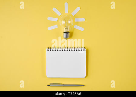 Financial planning table top with pen, notepad, light bulb on yellow background. Concept brainstorming and new idea Stock Photo