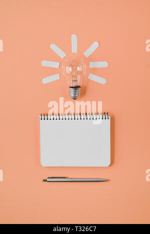 Financial planning table top with pen, notepad, light bulb on orange background. Concept brainstorming and new idea Stock Photo