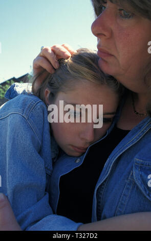 woman cradling anxious teenage girl against her chest Stock Photo
