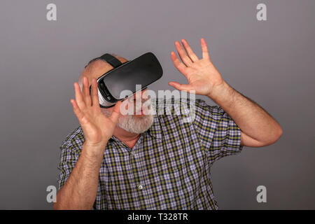 Man wearing virtual reality goggles. Studio shot, gray background Stock Photo