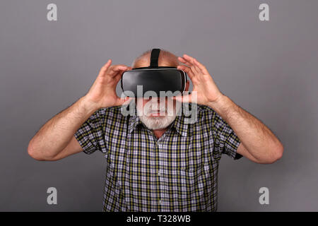 Man wearing virtual reality goggles. Studio shot, gray background Stock Photo