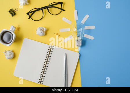 Flat lay financial planning brainstorming messy table top image with blank clip board, office supplies, pen, notepad, eyeglasses, coffee cup, light bu Stock Photo