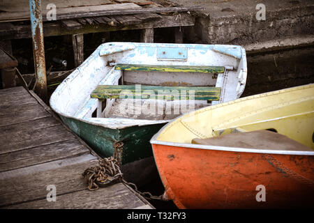 A few old shabby and worn boats different colors on the dock pier close-up Stock Photo
