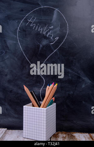 Wooden pens on a blackboard with the speech bubble Thinking Stock Photo