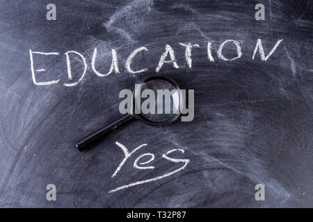 blackboard with the word education and yes and a magnifying glass Stock Photo