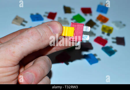 Car fuse in the man's hand. Many colorful electric automotive fuses or circuit breakers on a white background Stock Photo
