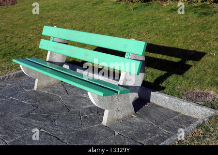 A green bench made of wood and concrete photographed on a sunny spring day in Nyon, Switzerland. In this photo you can also see some grass. Stock Photo