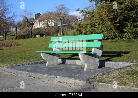 A green bench made of wood and concrete photographed on a sunny spring day in Nyon, Switzerland. In this photo you can also see some grass. Stock Photo