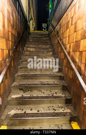 Old and worn stairs in subway station at night in New York City, USA Stock Photo
