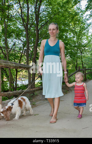Mother, girl toddler and Cavalier King Charles Spaniel, at Butler Trail in Zilker Park in Austin, Texas, USA Stock Photo