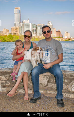 Father, mother, girl toddler and dog, at Lou Neff Point over Lady Bird Lake, downtown towers in distance, Zilker Park in Austin, Texas, USA Stock Photo
