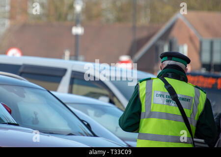 civil enforcement officer or traffic warden writes out parking ticket for vehicle in UK Stock Photo