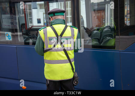 Stratford upon Avon Warwickshire England UK Mrch 23rd 2019 traffic warden otherwise known as civil enforcement officer writes out ticket for a bus par Stock Photo