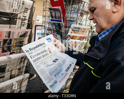 Paris, France - 29 Mar 2019: Newspaper stand kiosk selling press with senior male hand buying latest italian La republica featuring Economia anno zero on front cover Stock Photo