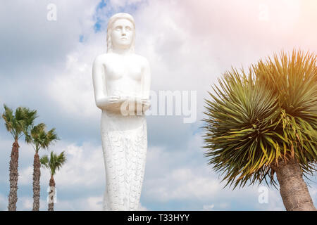 Mermaid statue in the park among palm trees. Stock Photo