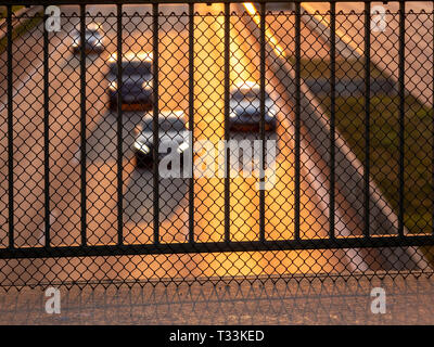 Image of metal safety barrier on brigde above highway with blurry cars and sun shine in the background Stock Photo