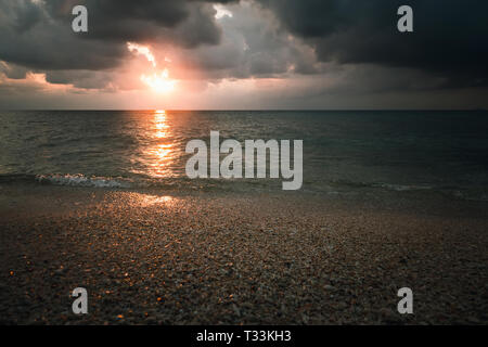 cloudy sunset over the sea in a rocky beach with stones and red dusk. epic sky. Andaman and Nicobar Islands. Neil to Havelock Goa Kerala India Stock Photo