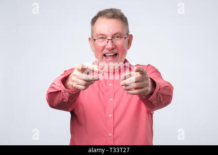 Hey you concept. Happy senior man in red shirt pointing at you. Studio shot Stock Photo