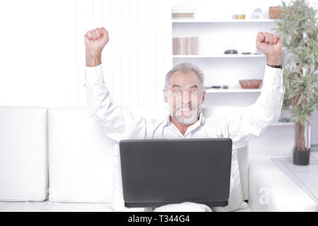happy businessman with laptop sitting on sofa at office Stock Photo