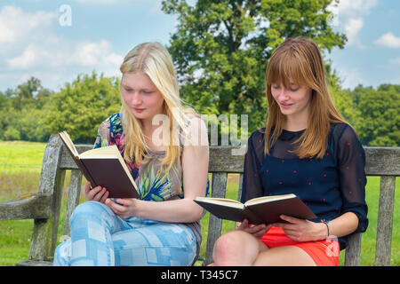 Two dutch teenage girls reading book on bench in nature Stock Photo
