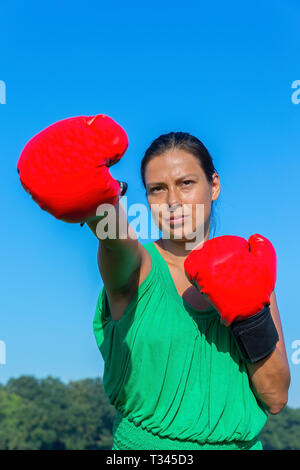 Young colombian woman wears red boxing gloves outdoors Stock Photo