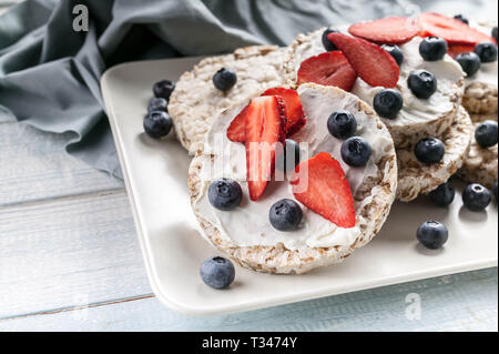 Puffed whole grain crispbread with curd cheese, fresh strawberries and blueberries. Close-Up. Healthy food Stock Photo
