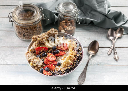 Organic breakfast. Healthy breakfast bowl: Cottage cheese, granola, bananas, strawberries, blueberries and puffed rice. Wooden table background Stock Photo