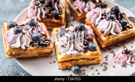 Close-Up Homemade Viennese waffles with cream, jam, blueberry and mint leaves. Delicious Dessert Stock Photo