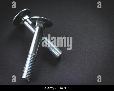 Metal bolts on a dark background. coach screws. Furniture bolts. Hardware Stock Photo