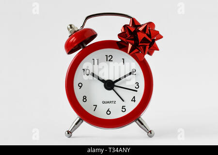 Red alarm clock with gift bow on white background - The gift of time concept; time for gift giving concept Stock Photo