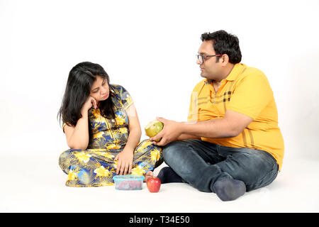 Man is giving coconut water pregnant lady. Isolated on the white background. Stock Photo