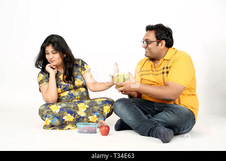 Man is giving coconut water pregnant lady with sitting on the floor. Isolated on the white background. Stock Photo