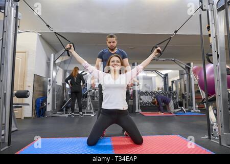 Kyiv UA, 28-03-2019 Mature woman doing exercise on decompression simulators with trainer rehabilitation. Sports physiotherapist assisting aged woman e Stock Photo