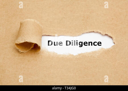 Text Due Diligence appearing behind torn paper. Concept representing the research done before entering into an agreement or contract as a part of the  Stock Photo