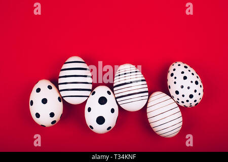 Different graphic hand-painted eggs on bright red background. Easter concept. Flat lay style. Stock Photo