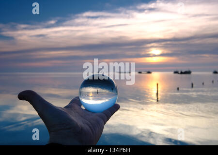Human hand holding a crystal ball by Sevre Niortaise river, Deux-Sevres, France Stock Photo