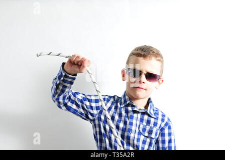 Boy with sunglasses and checked shirt holding a rope in his hands Stock Photo