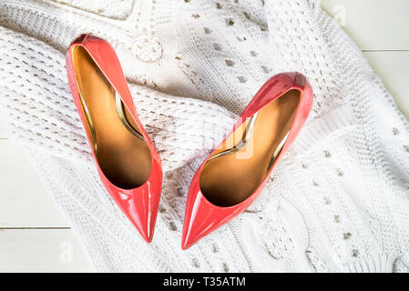Stylish Black Stiletto Shoes or High Heels on White Knitted Sweater, Flat Lay, Top View Stock Photo
