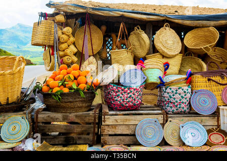 Craft wicker hats, oranges and other souvenirs in the market of Morocco Stock Photo