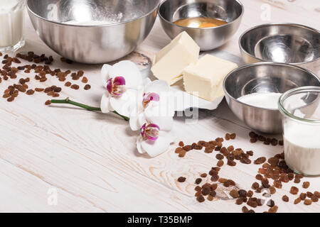 Ingredients for the Easter dough with text space. Eggs, flour, butter, raisins, dry yeast, sugar, milk, sour cream on white wooden background Stock Photo