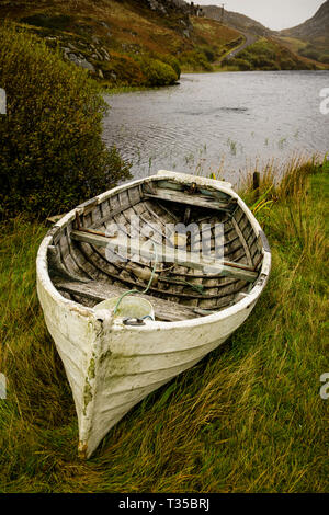 A derelict wooden rowboat sits on the shore of Loch Dubh in Tarbet, on the west coast of Scotland. Stock Photo
